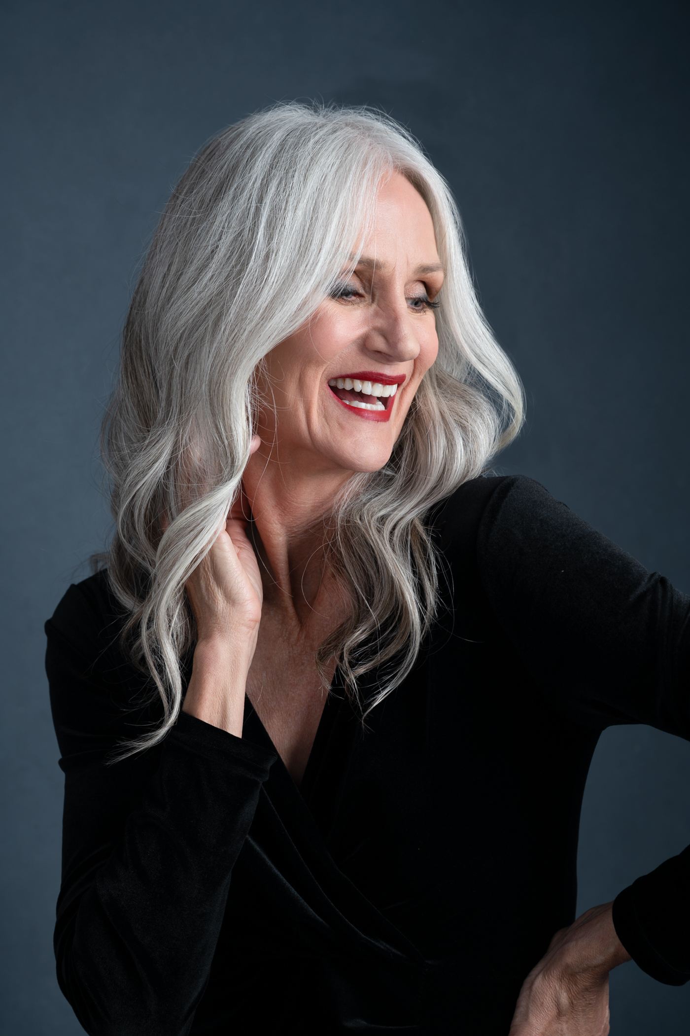 portrait of an older woman with white hair wearing a black dress and a big smile