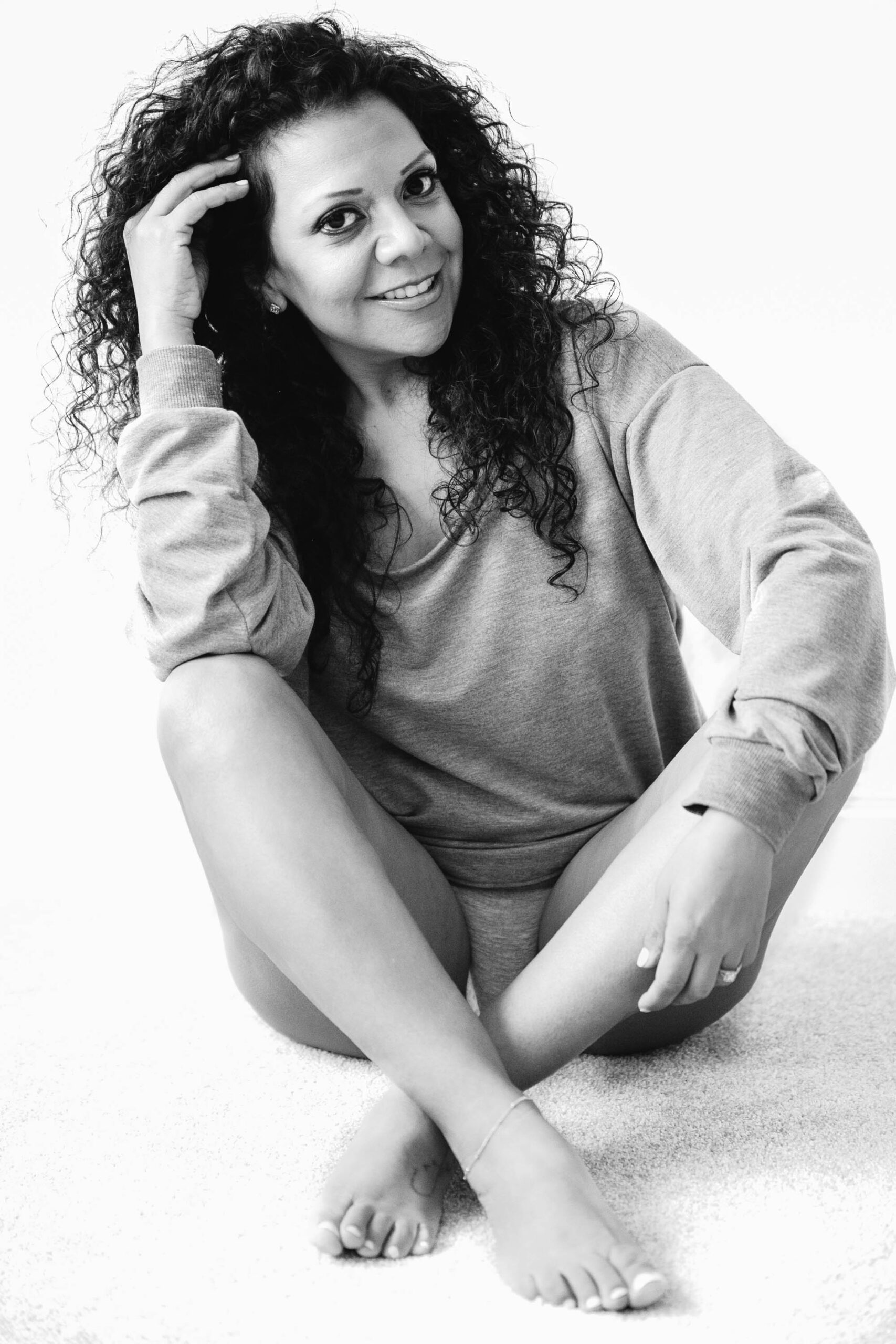 woman posing on the floor touching her hair and wearing only an oversized sweater
