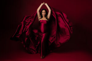 Photo of a pregnant woman in a red blackgournd covering her body with a red silk fabric tosing in to the sidesPhoto of a pregnant woman against a red background, draped in red silk fabric.Photo of a pregnant woman against a red background, draped in red silk fabric.Photo of a pregnant woman against a red background, draped in red silk fabric.