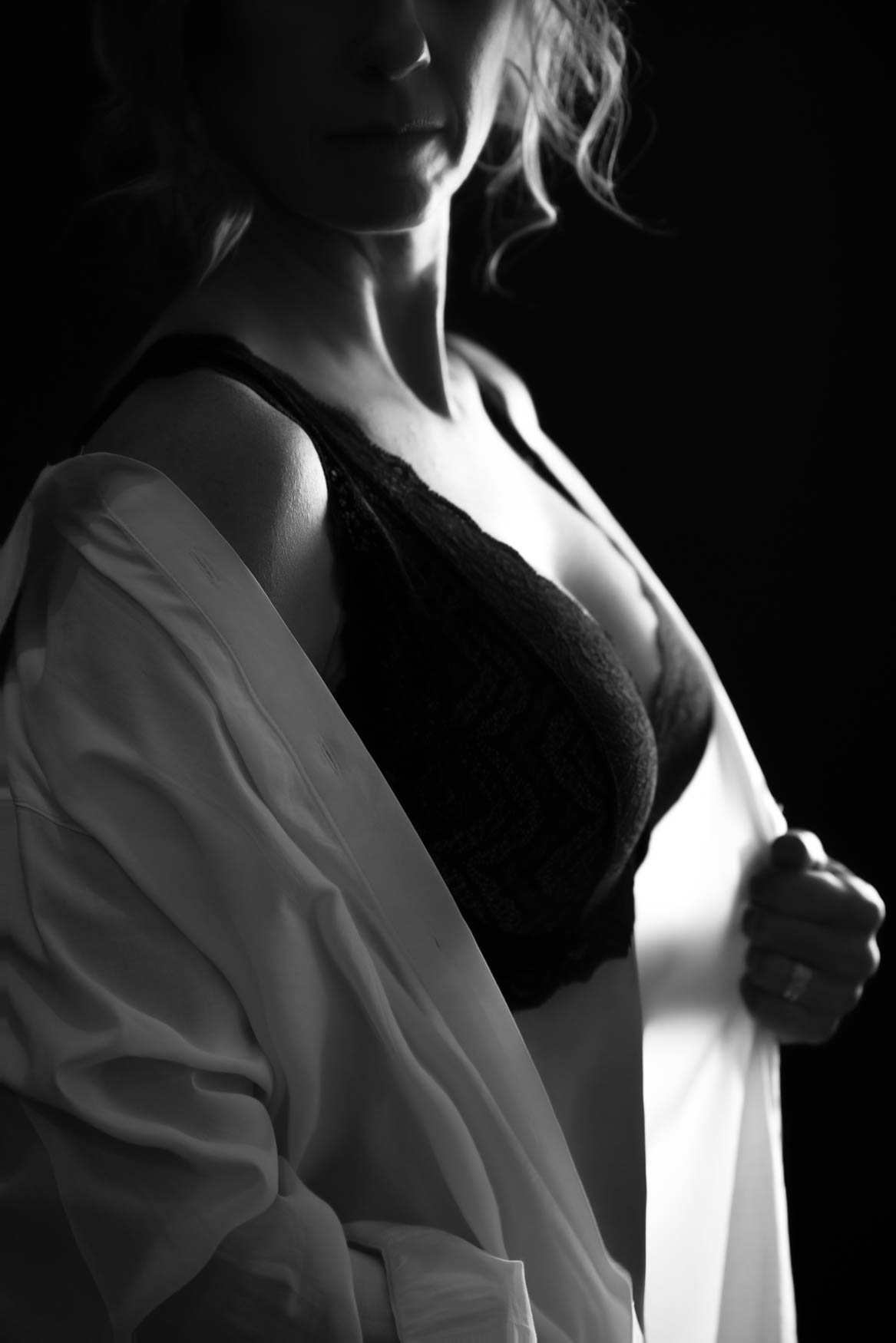 A woman wearing a black lace bra with white oversize shirt