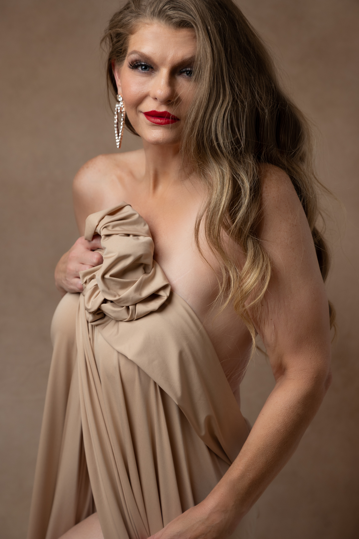 A mature blond woman wearing a brown sheet to cover her naked body