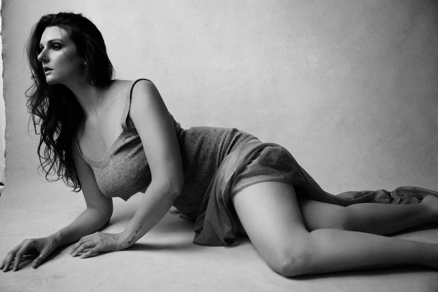 Woman laying down on the floor wearing a short dress showing her legs
