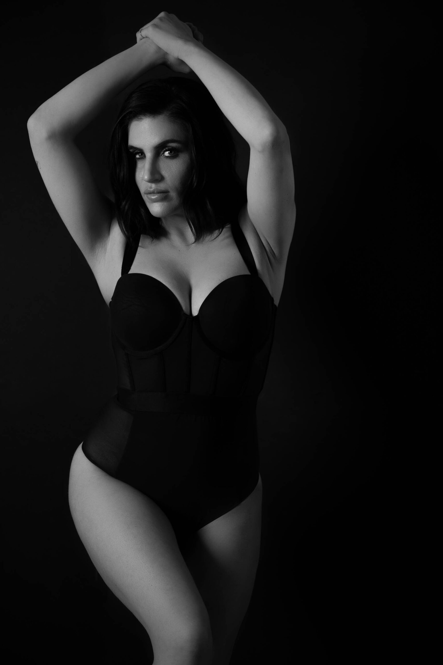 a black and white portrait of a woman wearing a black one-piece lingerie