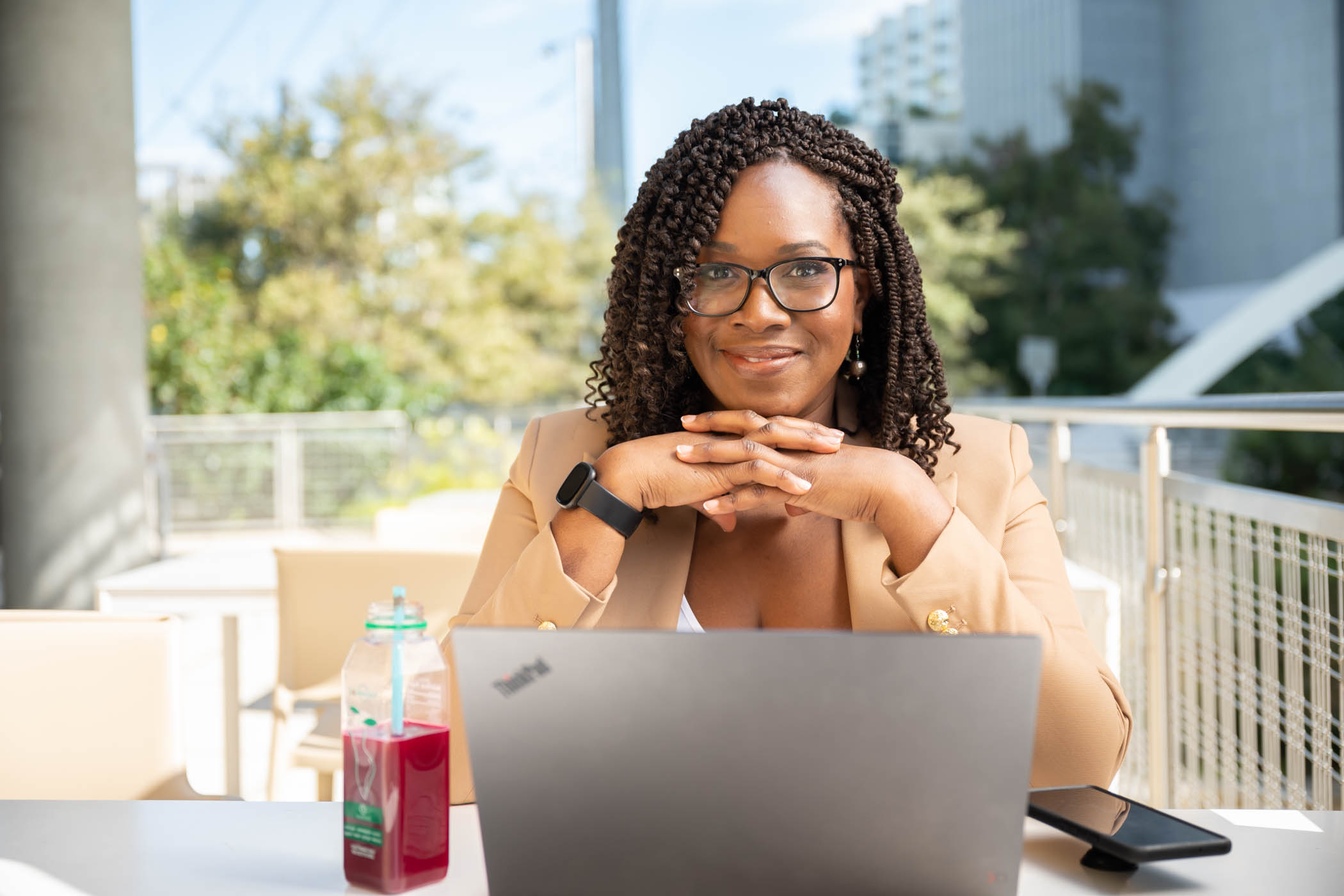 a woman sitting in an outdoor coffee place working on a computer