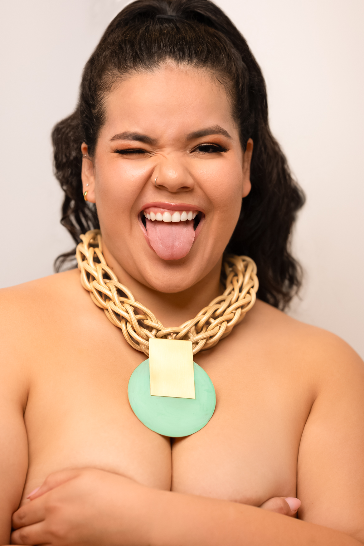 Playful portrait of a woman laughing and sticking out her tongue while wearing a statement gold necklace. Austin portrait photographer